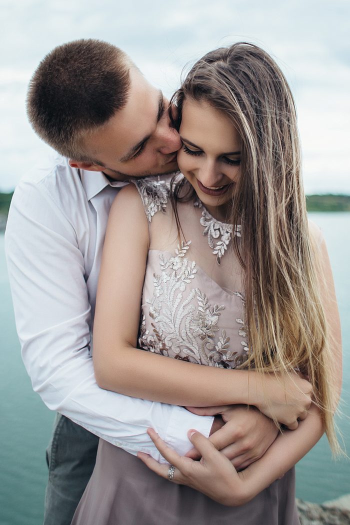 Noivo abraçando a noiva por trás e beijando seu rosto